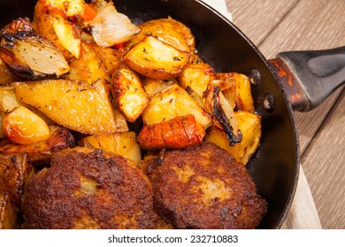 New potatoes and roasted cutlet in pan on wooden - Shutterstock ID 232710883