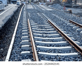 new and precise laying of tracks using leveling devices at the fork in two tram tracks. a layer of gravel above which concrete sleepers are placed. rubber anti-vibration base made of rubber
