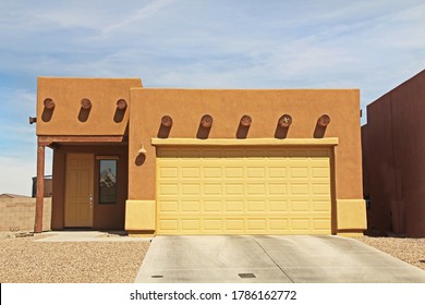 New ranch, burnt orange terra cotta and yellow, flat roof, stucco home in Tucson, Arizona, USA with beautiful blue sky and landscaping.