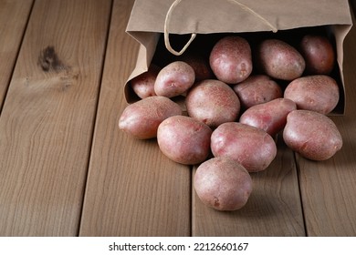 New Raw Red Potatoes In Paper Bag On Wooden Background