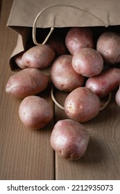 New Raw Red Potatoes In Paper Bag On Wooden Background.