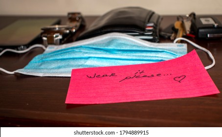 New Reality. Picture Of A Phone, Keys, Wallet, Watch Surgical Mask And Note On Side Table