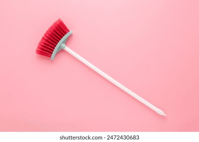 New red broom with white plastic stick for child on light pink table background. Pastel color. Closeup. Cleaning tool. Top view. - Powered by Shutterstock