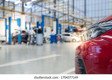 The New Red Car Is Beautiful, Luxurious, With A Car Repair Shop Background. Use The Electric Lift For Lifting Service Vehicles Placed On The Epoxy Floor.