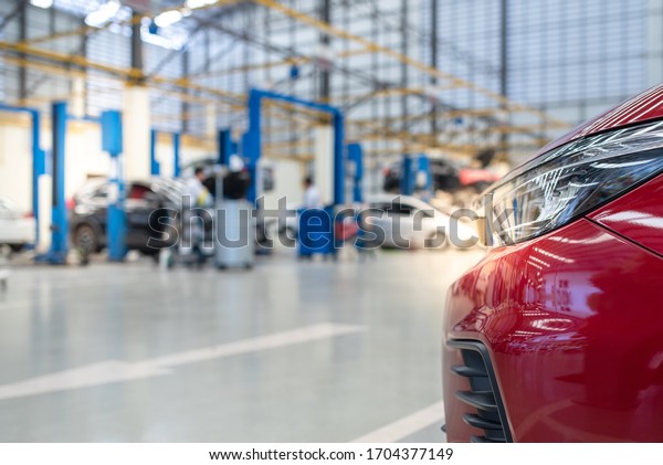 The new red car is beautiful,\
luxurious, with a car repair shop background. Use the electric lift\
for lifting service vehicles placed on the epoxy\
floor.