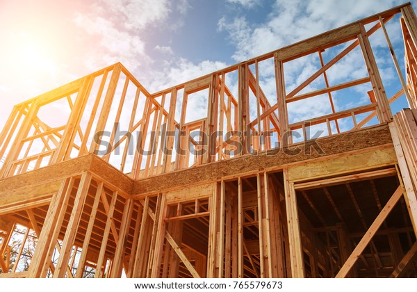 New residential\
construction home framing against a blue sky. Roofing construction.\
Wooden construction