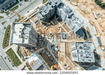 new residential district under construction. construction site with yellow tower cranes and machinery. aerial top view.
