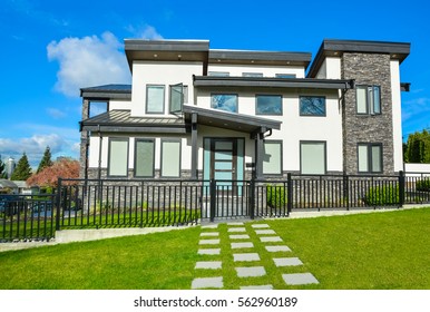 New Residential House With Concrete Tile Pathway Over Front Yard Lawn And Metal Fence In Front