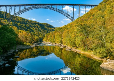 New River Gorge Bridge scenic view in fall. View from the lower gorge with reflection of the bridge in the river and fall foliage on the mountain sides.  Horizontal color photo. 