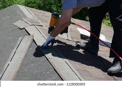 New Roof Shingle Being Applied. A Roofer Nailing Asphalt Shingles With Air Gun.