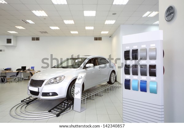 New shine car stands in office\
of shop selling cars near stand with samples of paint for\
body.