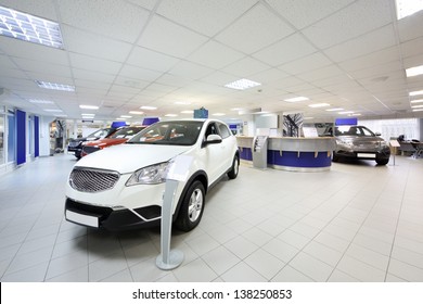 New Shining Beautiful Cars Stand Near Desk Reception In Car Shop.