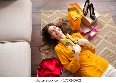 New Shoes. Smiling Young Girl Lying On The Floor And Holding New Shoes