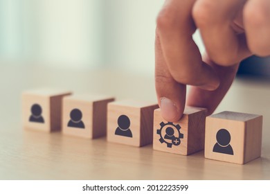 New skills concept to develop performance of human resources for business growth and digital transformation. Man holds wood cube with new skills icon symbol on many staff icon symbol; copy space. 