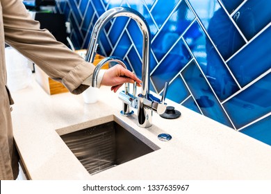 New Small Modern Faucet And Kitchen Sink Closeup With Woman Turning On Handle And Blue Vibrant Backsplash And Shiny Clean Stainless Steel Handle