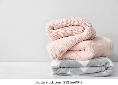 New soft folded blankets on table near light wall