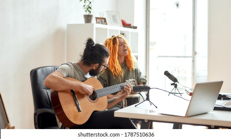 New Song. Man playing guitar and woman singing. Couple of musicians recording video blog or vlog while making music at home. Focus on man. Web Banner - Powered by Shutterstock