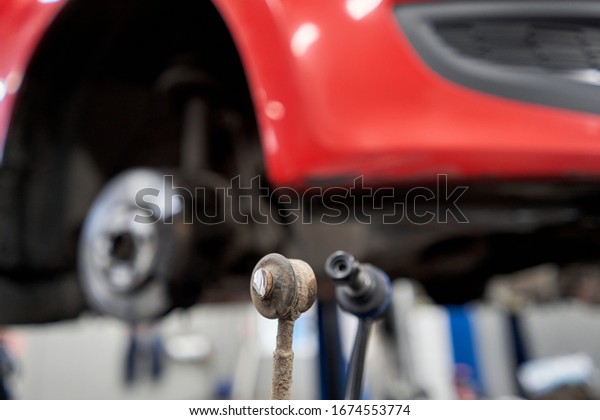 New stabilizer bar or link arm ready to\
replacement into car suspension in garage for repair and\
maintenance. Car part and suspension\
concept