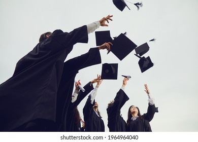 New Stage Of Life. Graduates Toss Their Academic Hats Into The Sky During A Solemn Ceremony At The University. Students Make A Gesture Of Successful Graduation. Education, Graduation And Alumni.