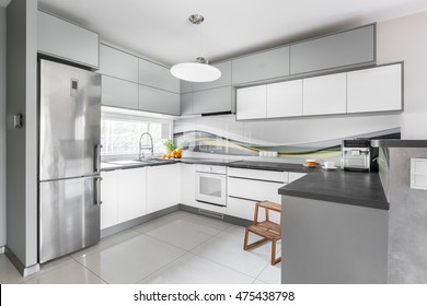 New Style Light Kitchen Interior With Functional Furniture, Silver Fridge, Wooden Step Stool, Window And High Gloss Flooring