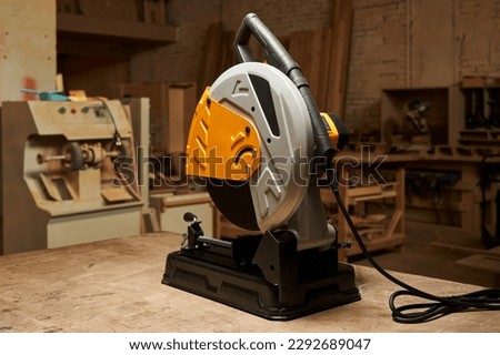 A new stylish cutting off abrasive disc machine stands on a wooden workbench in a carpentry workshop