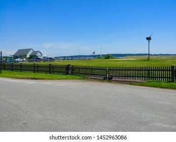 New Suffolk, NY - June 27 2019: View of a fence surrounding a field and an osprey nest on First Street
