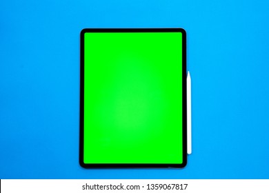 new tablet on a Blue background with a keyboard and pen, and green screen