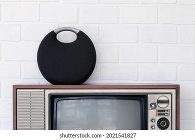 A New Technology Bluetooth Speaker Sits On Top Of An Old Vintage Television Set.