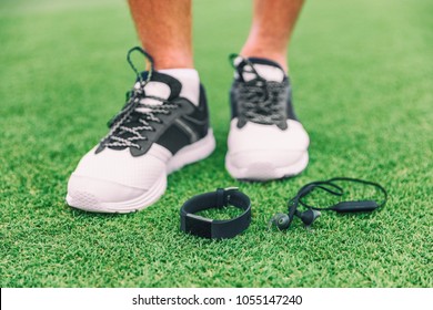 New Technology Sport Wearable Accessories For Runners: Fitness Sports Smart Watch And Wireless Earphones Man Running Shoes. Earbuds, Smartwatch On Grass. Tech Run Gear, Smart Jogging.