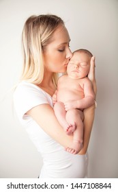 New Teen Mother Holding And Kissing Newborn Baby Girl In Arms On