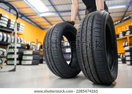 new tires Car mechanic brings new tires in stock 2 lines to the tire shop to change the wheel of the car at the service center or garage for the automotive industry.