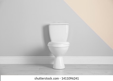 New toilet bowl near color wall indoors