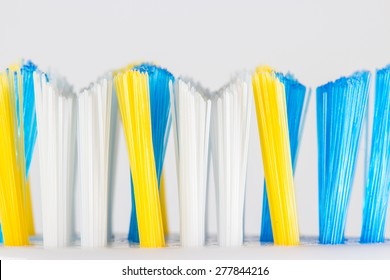 New toothbrush with yellow, blue and white bristles on the plastic base on a white background. Shot in macro. - Powered by Shutterstock