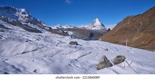 A New Trail To The Monte Rosa Hut That Crossing Gorner Glacier With A Lot Of Crevasses. Mounts Matterhorn And Breithorn At Background. Trail Marked By Long Poles Above The Glacier. A Sunny Autumn Day.