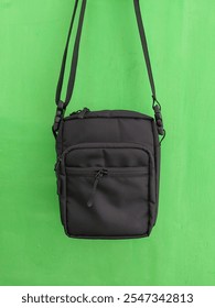 new trendy modern casual small black fabric men's shoulder bag with strap on green background