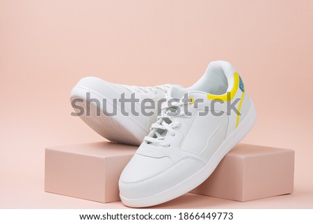 new trendy white sports sneaker on a stand on a pink background