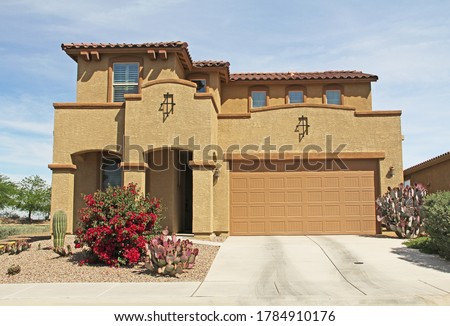 New two-story, brown and tan beige stucco home in Tucson, Arizona, USA with beautiful blue sky and landscaping.