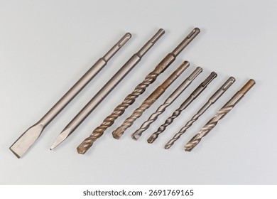 New and used replaceable working tools for rotary hammer drill, including flat and pointed chisel, masonry, concrete drill bits and twist metal drill, top view on a gray background 