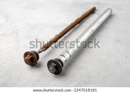 New and used rod to protect the boiler against rust on a gray concrete background