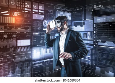 New vision. Clever enthusiastic young programmer feeling interested while being in his modern futuristic office and wearing amazing virtual reality glasses - Shutterstock ID 1041689854