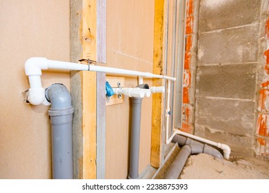 New water installation, exposed mounted grey PVC sewerage pipes mounted on the plasterboard wall.