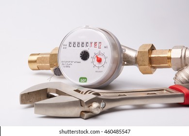 New water meter with fittings and wrench on a white background. Sanitary equipment.