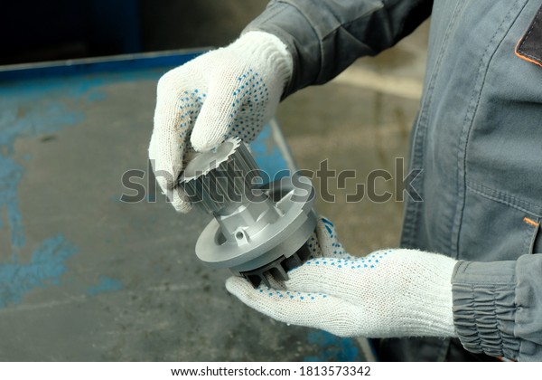 New water pump in the hands of a car mechanic\
close-up. Quality control of the part before installation on the\
repaired car in the service\
center.