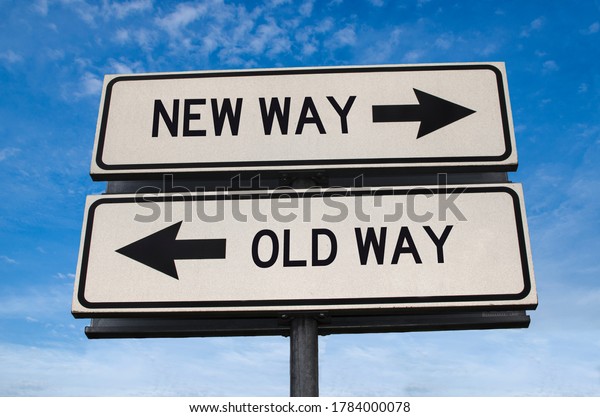 New way versus old way road sign. White two street\
signs with arrow on metal pole with word. Directional road.\
Crossroads Road Sign, Two Arrow. Blue sky background. Two way road\
sign with text.