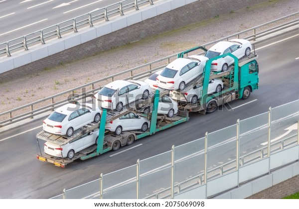 New white autos coming, transportation of\
cars on a truck trailer on a city\
highway