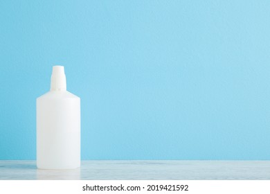 New White Bottle Of Hydrogen Peroxide On Table At Light Blue Wall Background. Pastel Color. Closeup. Front View. Product For Skin Wound Cleaning. Empty Place For Text Or Logo.