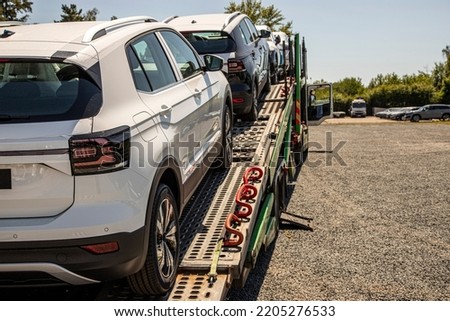 New white crossover - SUV on car carrier trailer, car-carrying trailer, car hauler, auto transport trailer, semi-trailer. Rear view car. Rear view trailer. Visible taillamps.