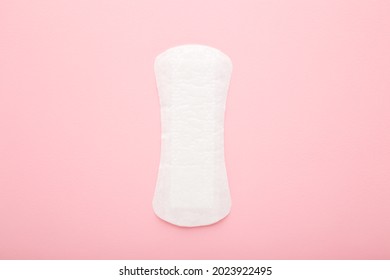New white panty liner on light pink table background. Pastel color. Closeup. Female daily hygiene.