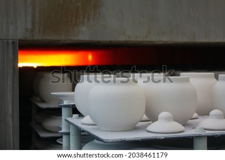 New white porcelain tableware is placed in a muffle kiln for firing close-up at a ceramic factory