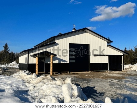 “Brand new white post-frame pole barn with sleek black metal roof. Clean lines and solid construction. Ideal for storage or agricultural use, this modern building blends functionality with style.”